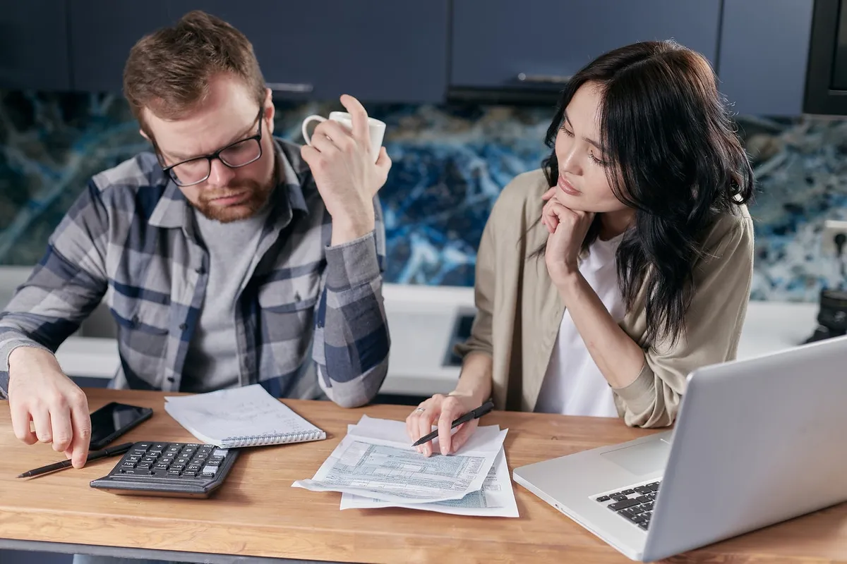 Pareja revisando facturas y cuentas en la mesa de una cocina
